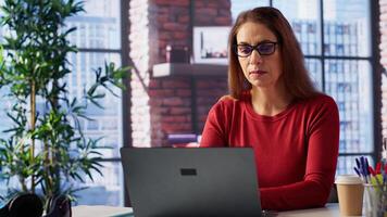 Mature person overseeing business schedule and planning activities at desk, working on time management with digital tools. Female freelancer utilizing the pc and multitasking. Camera A. photo