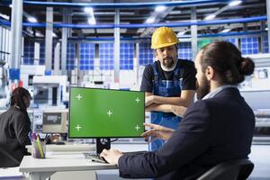 Solar panels plant engineering team doing quality control using green screen computer, ensuring high efficiency. Photovoltaics factory coworkers calibrating assembly lines robotic arms on mockup PC photo