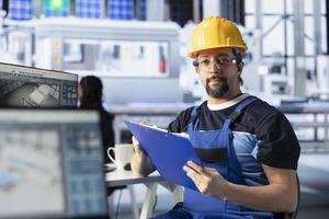 Portrait of engineer in photovoltaics factory reviewing paperwork to diagnose malfunctioning systems. Solar panels plant staff member reading inspection data files to reduce downtime photo