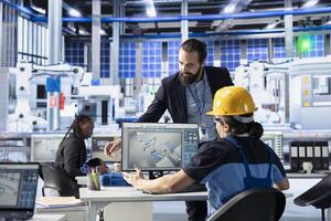 Industrial automation specialists in high tech solar panel plant adjusting robotic machinery settings through software interface. Photovoltaics factory experts diagnosing equipment performance issues photo