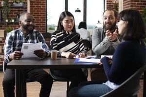 Friendly multiracial HR managers interviewing female candidate at a table, asking about her experience. Diverse recruitment team discussing with potential job applicant. Hiring concept. photo