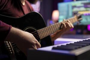Young artist playing guitar and creating music using daw software interface on computer, recording audio files. Musician composing songs in home studio and mixing acoustic sounds. Close up. photo