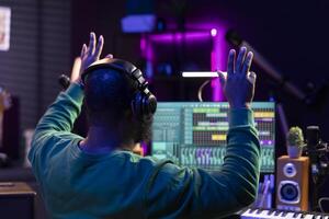 African american sound designer counting down before he starts the recording session, working with mixing console and software for editing in post production. Producer making music in home studio. photo