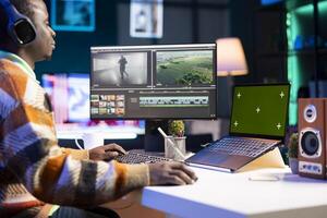African american man editing film footage on his dual monitors, creating content for cinematography next to copy space. Workspace organized for productivity, using editing software and multitasking. photo