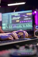 Sound engineer working with soundboard and midi controller to create the perfect tunes for his songs, recording and editing audio. Music composer adjusts volume levels during mixing sessions. photo