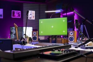Empty home studio equipped with mixing instruments and devices, soundboard console and mastering panel used for recording music. Greenscreen display on computer, signal processing. photo