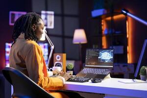 Teleworking programmer using laptop for artificial intelligence computing through self learning algorithms. African american remote worker working with AI deep neural networks on notebook photo