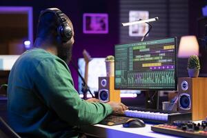 Pleased sound engineer adding piano notes on his audio recordings, creating special effects on new music. Artist composer mixing acoustics on his old songs, professional software interface. photo