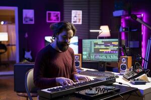 Young musician playing songs on piano midi controller in home studio, recording new tunes using daw software and mixing gear. Songwriter composing music on electronic keyboard equipment. photo