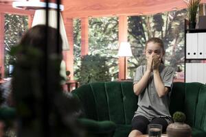 Troubled teen expressing her anxiety and mental health issues during a therapy session with psychologist, low confidence and internal frustration. Scared confused girl with personal troubles. photo