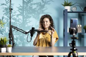 Internet show host using smartphone on phone holder, filming content about best gaming laptops. Media star recording notebook device review for interested viewers using mobile phone photo