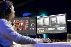 Freelancer adds sound effects to filmed footage, working in home studio, listening music. Post production specialist using headphones to test and improve audio quality using editing application photo
