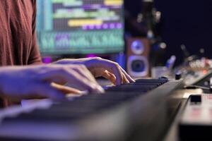 Music producer playing tunes on electronic midi controller, composing songs to use with mixing and mastering techniques. Singer plays electronic piano notes to create soundtracks. Close up. photo