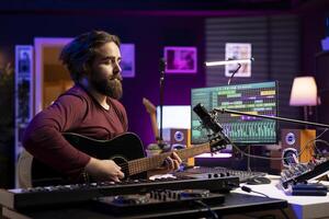 Musical composer singing tunes on acoustic instrument, working in his personal home studio to record a song. Sound engineer recording music, editing with mixing console. Acoustical engineering. photo