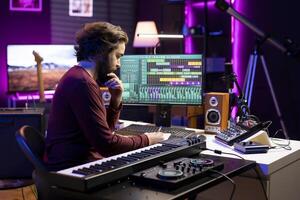 Young producer writing rhymes and words to create new music in home studio, thinking about harmonic notes and elements to compose a beautiful song. Audio engineer produces tunes. photo