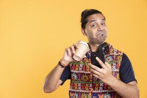 Portrait of man surprisingly pleased after sipping good coffee, texting friends. Overjoyed person satisfied with tasty hot beverage, having positive facial expression, studio backdrop photo