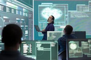 Professional hacker using ransomware and phishing tactics to compromise networks and gather intelligence for national security during cyberwarfare. Governmental spyware on big screen. photo