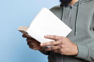 African american man reading book aloud and narrating story for audience. Person enjoying literature novel, reciting from pages, entertaining spectators against studio background. Close up. photo