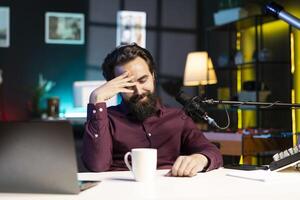 Influencer in home studio doing live broadcast for online streaming platforms, talking with fans, sharing embarrassing story. Blushing media star feeling flustered while telling viewers about himself photo
