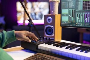 Music producer mixing sounds with stereo console and piano notes over his audio files, editing tracks with DAW software and producing new music. Composer musician operates on mixing console. photo