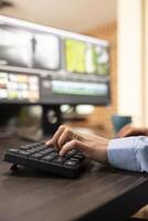 Closeup of a person using computer keyboard at office desk during their editing session. Selective focus on female hands seated at workstation, typing and improving film montage visual quality. photo