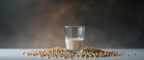 Fresh soy milk in a glass surrounded by soybeans on a dark background. photo
