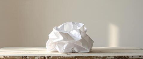 Crumpled white paper sheet on wooden surface with light and shadows photo