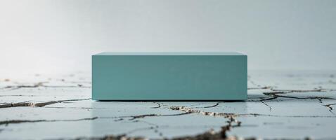 Rectangular teal object resting on cracked white surface photo