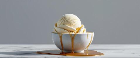 Vanilla ice cream scoop in ceramic bowl with drizzle of caramel syrup set on marble table for gourmet frozen dessert presentation. photo