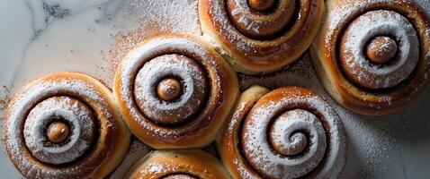 Overhead View of Four Glazed Cinnamon Rolls on a Textured White Surface with Powdered Sugar photo