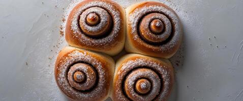 Overhead View of Four Glazed Cinnamon Rolls on a Textured White Surface with Powdered Sugar. photo