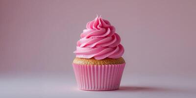A single cupcake with pink frosting in a pink wrapper on a pink background in a studio shot photo