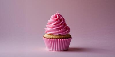 A single cupcake with pink frosting in a pink wrapper on a pink background in a studio shot. photo