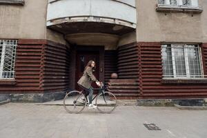 Cyclist dressed in tweed riding a vintage bicycle in front of a retro building photo