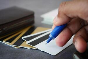 Writing on a blank card while surrounded by various cards and a wallet photo