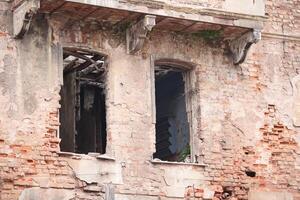 Old brick building with broken windows in a state of decay photo