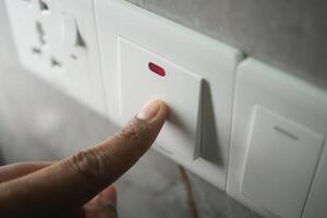 Person pressing a switch for electrical control in a home setting photo