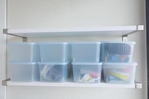 Organization of storage containers on a white shelf in a tidy space photo