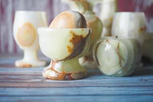 Unique onyx cups and decorative items displayed on rustic wooden table photo