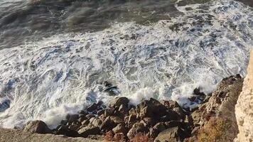 Waves crashing on a rocky shore. Dramatic seascape with white foam and turbulent water. Use for travel, nature, power, or coastal resilience concepts. video