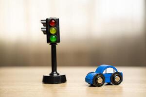 A toy blue car near a traffic light on the table. Traffic and driving rules concept photo