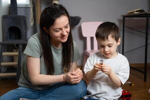 Little boy studying a light bulb with his mother. Educational games, learning about the world. Sparking curiosity about science, energy, and inventions. Understanding of technology and innovation. photo