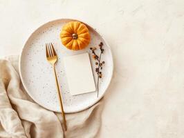 Autumn table setting with mini pumpkin and golden cutlery on white plate photo