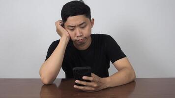 Asian man sitting at table checking mobile phone feels worry and serious video