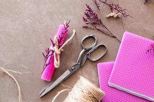 Crafting supplies with pink beeswax candles, scissors, and twine on brown surface photo