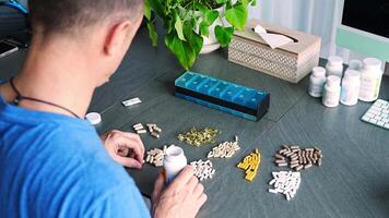 Man sorting his pills and supplements into a weekly pill organizer. Concept of medication management and daily health routine. High quality 4k footage video