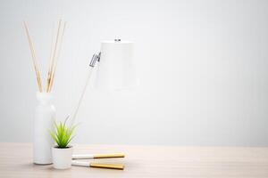 Reed diffuser with lamp and small plant on wooden table in copy space and workspace concept. photo