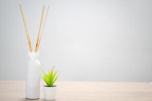Reed diffuser and small plant on wooden table in bedroom photo
