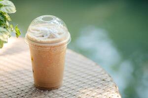 Glass of iced frappe coffee on wooden table in coffee shop, copy space and isolate concept. photo