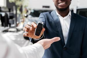 Happy client receiving the keys to their new car from a dealership representative. Close-up. The concept of test drive, buying an electric car or renting. Banner, free copy space, advertising photo